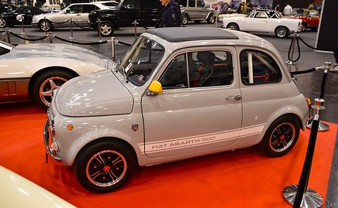 Pale grey Fiat 500 with Fiat Abarth 595 lettering along its sill and red-centred wheels, on red carpet behind a rope. Opens a larger view