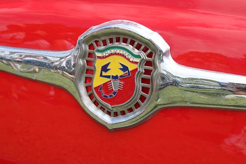 Chrome moustache trim on red paint, holding a red, yellow and green enamel shield with a blue scorpion. Opens a larger view