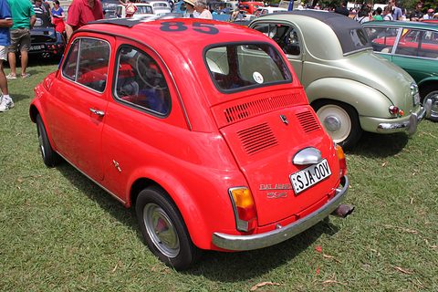 Red Fiat 500 seen from the rear left with a louvred engine lid and NSW plate, a pale green saloon beside it. Opens a larger view