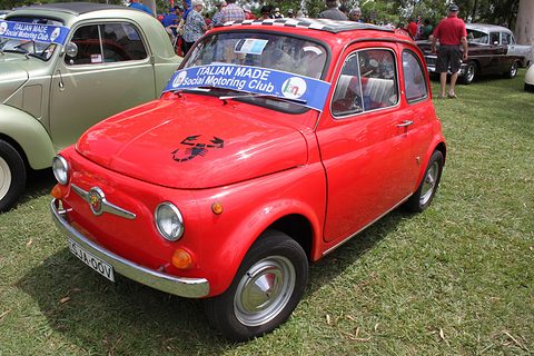 Red Fiat 500 with a black scorpion decal on the bonnet, a club sun strip and a chequered roof, on grass. Opens a larger view