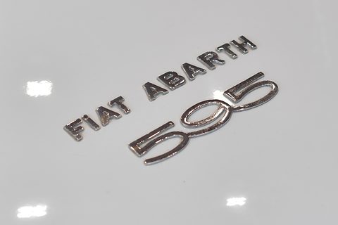 Chrome lettering reading FIAT ABARTH above a large stylised 595 on a glossy white panel. Opens a larger view