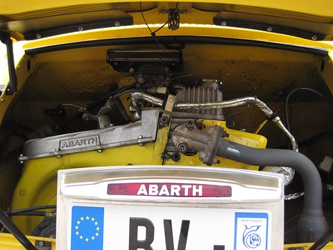 Engine bay with an aluminium Abarth-lettered cover, a large air filter box and foil-wrapped pipes behind a number plate.