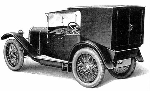 A small dark van with a box body, an open cab and wire wheels, shown from the front quarter on a white ground. Opens a larger view