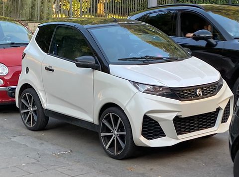 White small car with a black roof, angular grille and black alloy wheels, between a red Fiat and a black car. Opens a larger view