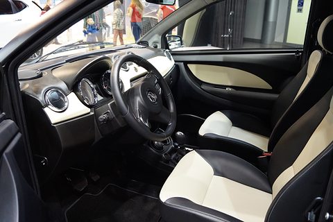 Black and cream leather seats, cream door panel and black dashboard seen through the open driver’s door. Opens a larger view