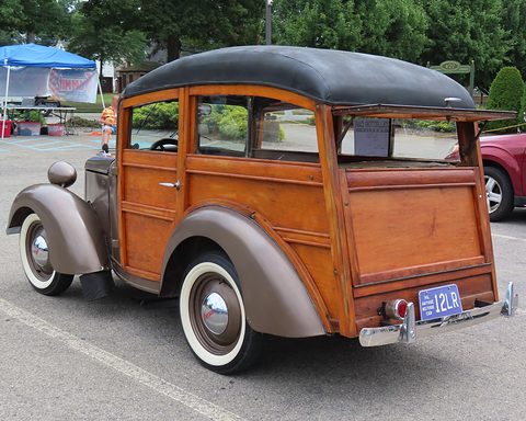 The rear of a small wooden-bodied station wagon with a black roof and a tailgate. Opens a larger view