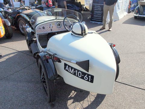 The pointed white tail of a sports two-seater with a Dutch number plate and a fin-like headrest. Opens a larger view