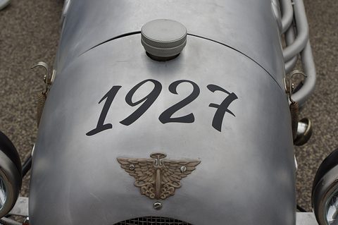 A grey rounded tail with a filler cap, 1927 painted in black script and a winged badge. Opens a larger view