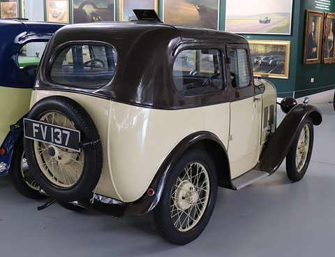 The rear of a cream saloon with a brown domed roof and a spare wheel on its tail. Opens a larger view
