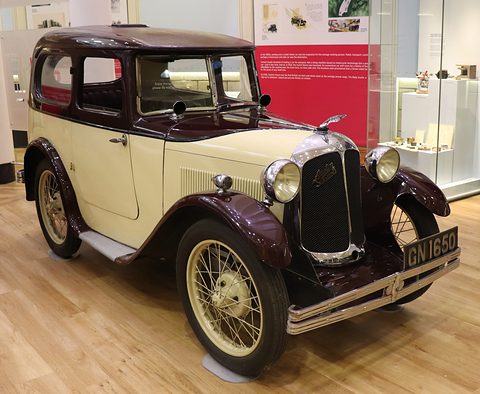 A cream saloon with a brown roof and wings, a polished radiator and wire wheels on a wooden floor. Opens a larger view