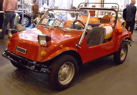Orange doorless open car with square headlamps on the wings, black seats and a beach ball in the back.