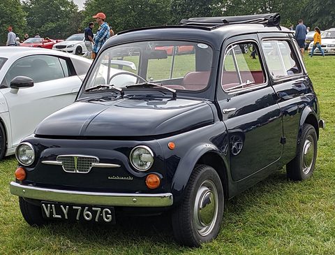 Dark blue small estate car with an Autobianchi badge on grass beside a white sports car.