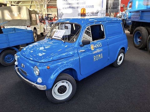 Blue windowless small van with an orange roof beacon and ‘ANAS Roma’ lettering in a show hall.