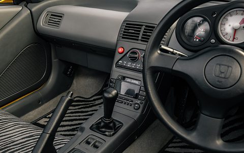 Grey dashboard with three round dials behind a Honda steering wheel and zebra-striped seat fabric.