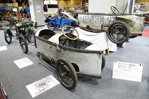 Rear of two weathered narrow cyclecars, one behind the other, with a steering wheel at the back seat. Opens a larger view