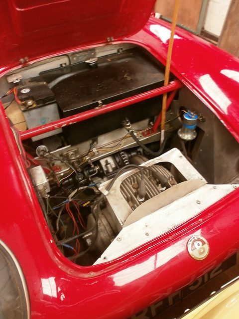 Engine and wiring seen from above inside an open red glass-fibre bonnet. Opens a larger view