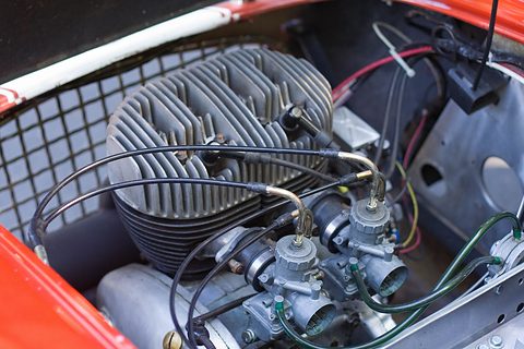 Finned two-cylinder engine with two carburettors and a mesh grille ahead of it