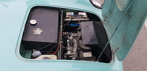 Engine and battery inside a turquoise glass-fibre bay with the bonnet raised. Opens a larger view