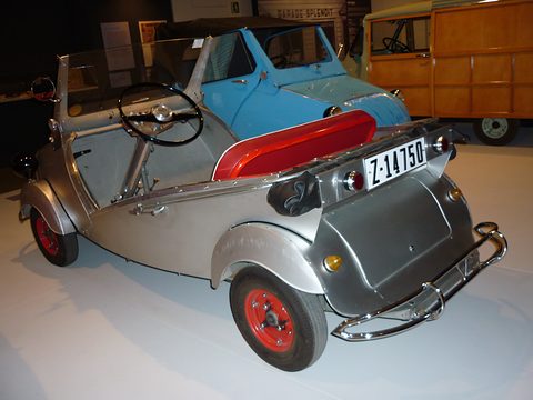 Silver doorless open car seen from the rear right, red bench seat, tubular bumper and a Zaragoza number plate. Opens a larger view
