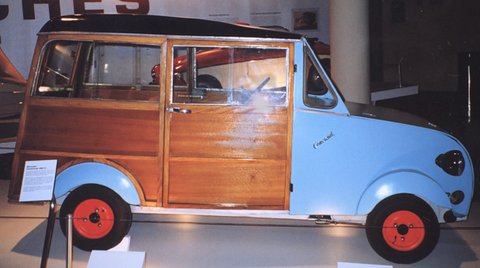 Side view of a pale blue estate with varnished wooden rear body and doors, red wheels and a ‘Comercial’ script on the bonnet side. Opens a larger view