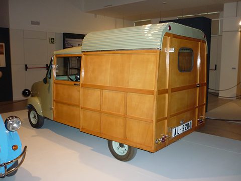 Rear quarter of a small van with a varnished wooden box, rear door window and a curved green roof. Opens a larger view