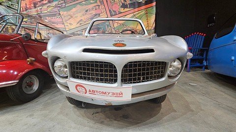 Silver open sports body with two mesh grilles and round headlamps, a museum name board fixed below the grille. Opens a larger view