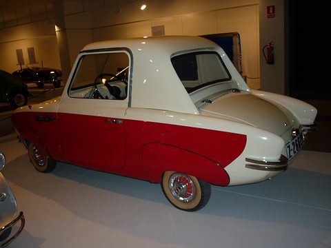 Rear quarter of a cream and red coupé with a rounded cream roof and chrome-tipped pointed rear wings. Opens a larger view