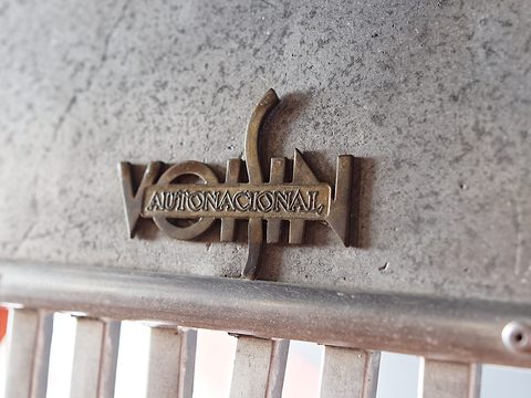 Bronze-coloured badge reading VOISIN with AUTONACIONAL across it, on a weathered silver nose above grille bars.