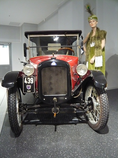 Front view of a red tourer with a black radiator and plate 439, a costumed mannequin beside it. Opens a larger view