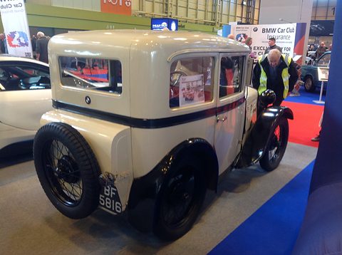 Rear three-quarter view of a cream saloon with a spare wheel on its tail and plate BF 5816 on a show stand. Opens a larger view