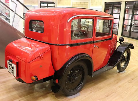 Rear three-quarter view of a red saloon with a rounded tail and a BMW DIXI plate on a wooden floor. Opens a larger view