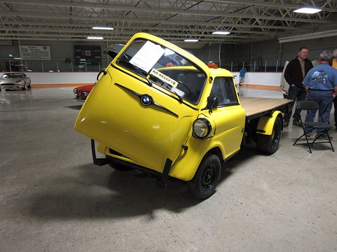A yellow bubble-fronted BMW with its front door, cut down behind the cab to a wooden flat bed. Opens a larger view