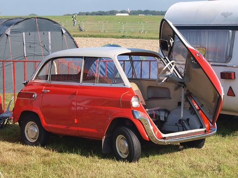 Red car with its whole front panel opened sideways, revealing the white steering wheel, column and beige interior.