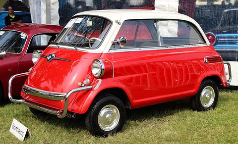 Red small car with white roof on grass beside a marquee, chrome tubular bumpers and a Bonhams sign at the wheel. Opens a larger view
