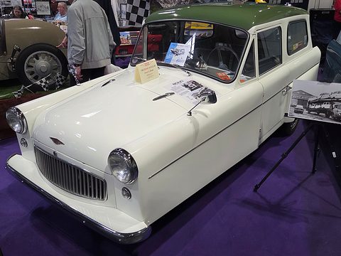 Cream three-wheel estate with a green roof and chrome grille on a purple show carpet. Opens a larger view