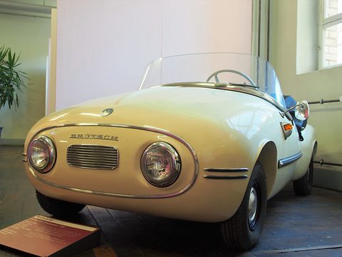Cream rounded nose with two round headlamps either side of a small chrome grille, museum sign at left. Opens a larger view