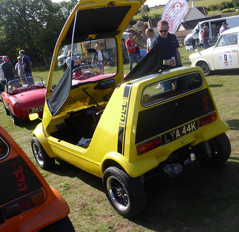 Yellow car from behind with its canopy up, black tail panel and wide rear axle. Opens a larger view
