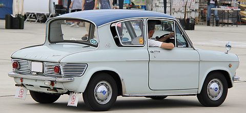 Side view of a pale blue two-door saloon with a dark blue roof, a driver resting an arm on the door.