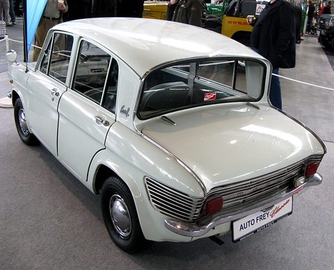 Rear three-quarter of a white four-door saloon with a louvred tail and an AUTO FREY plate. Opens a larger view