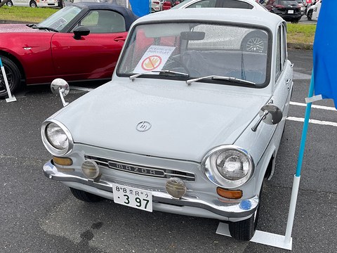 Pale grey four-door saloon seen from the front with round headlamps and a chrome bumper. Opens a larger view