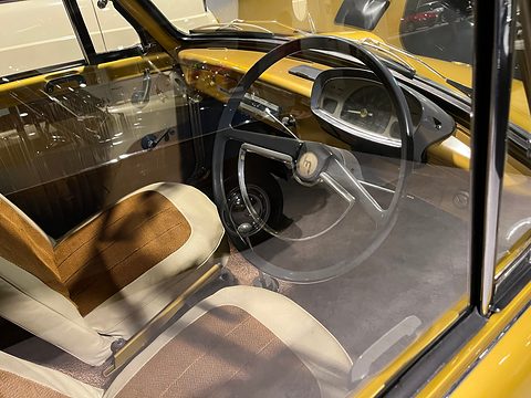 Through an open door: a thin two-spoke steering wheel, a gold-painted dashboard and cream seats. Opens a larger view