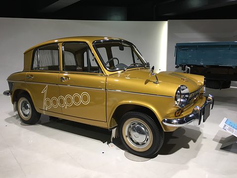 Gold four-door saloon with a large 1,000,000 script on its doors, in a white gallery.