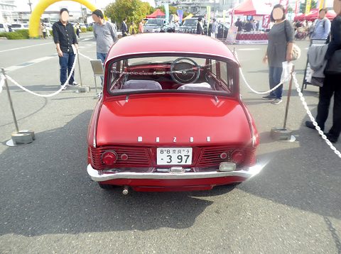 Rear view of a red saloon with a louvred tail, chrome MAZDA letters and a Nara number plate. Opens a larger view