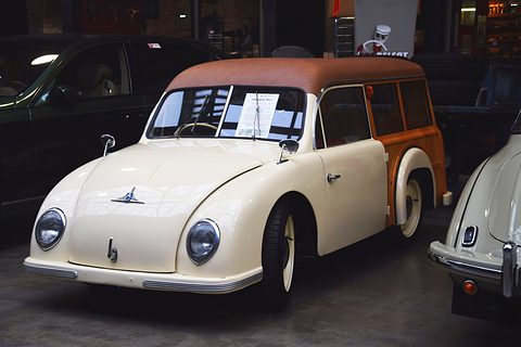 Cream small estate car with a brown roof and wood-panelled rear, a sale sheet on the windscreen.