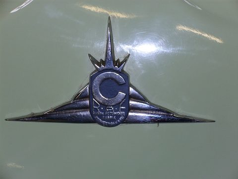 Chrome winged emblem with a blue C shield on pale green paint. Opens a larger view
