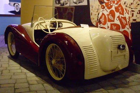 Cream engine cover with rows of louvres and maroon wings over yellow wire wheels. Opens a larger view