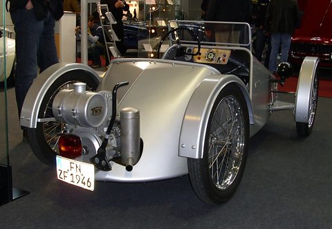 Silver doorless roadster from behind, its small engine and exhaust exposed, plate FN ZF 1946. Opens a larger view