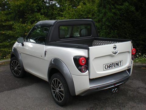 Rear of a white small pick-up with a chequer-plate bed lining, round tail lamps and twin exhausts. Opens a larger view
