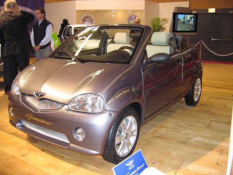 Purple-grey small open two-seater with cream seats and Speedino script on its bumper, on a wooden floor.