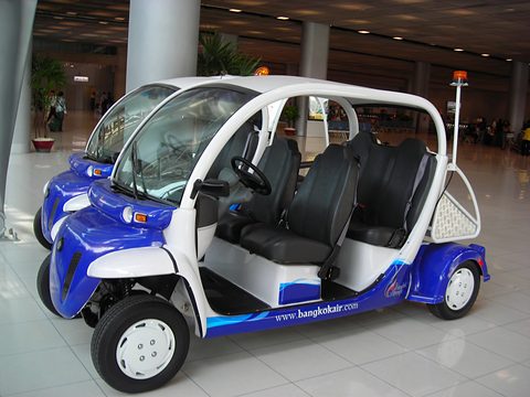 Blue and white open six-seat electric shuttles with bangkokair.com lettering on a polished terminal floor. Opens a larger view